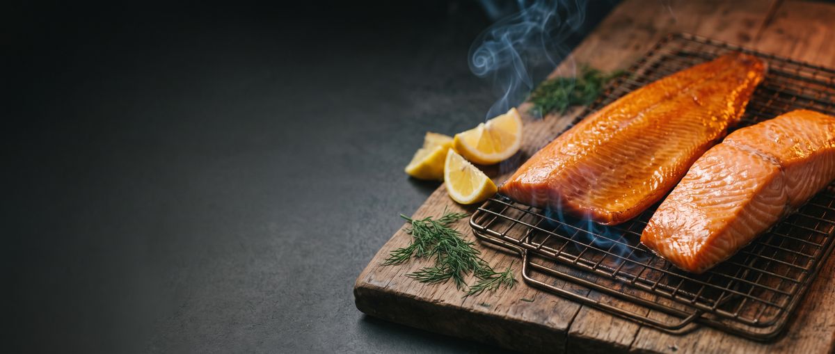 Two smoked salmon fillets on a rack with lemon and dill