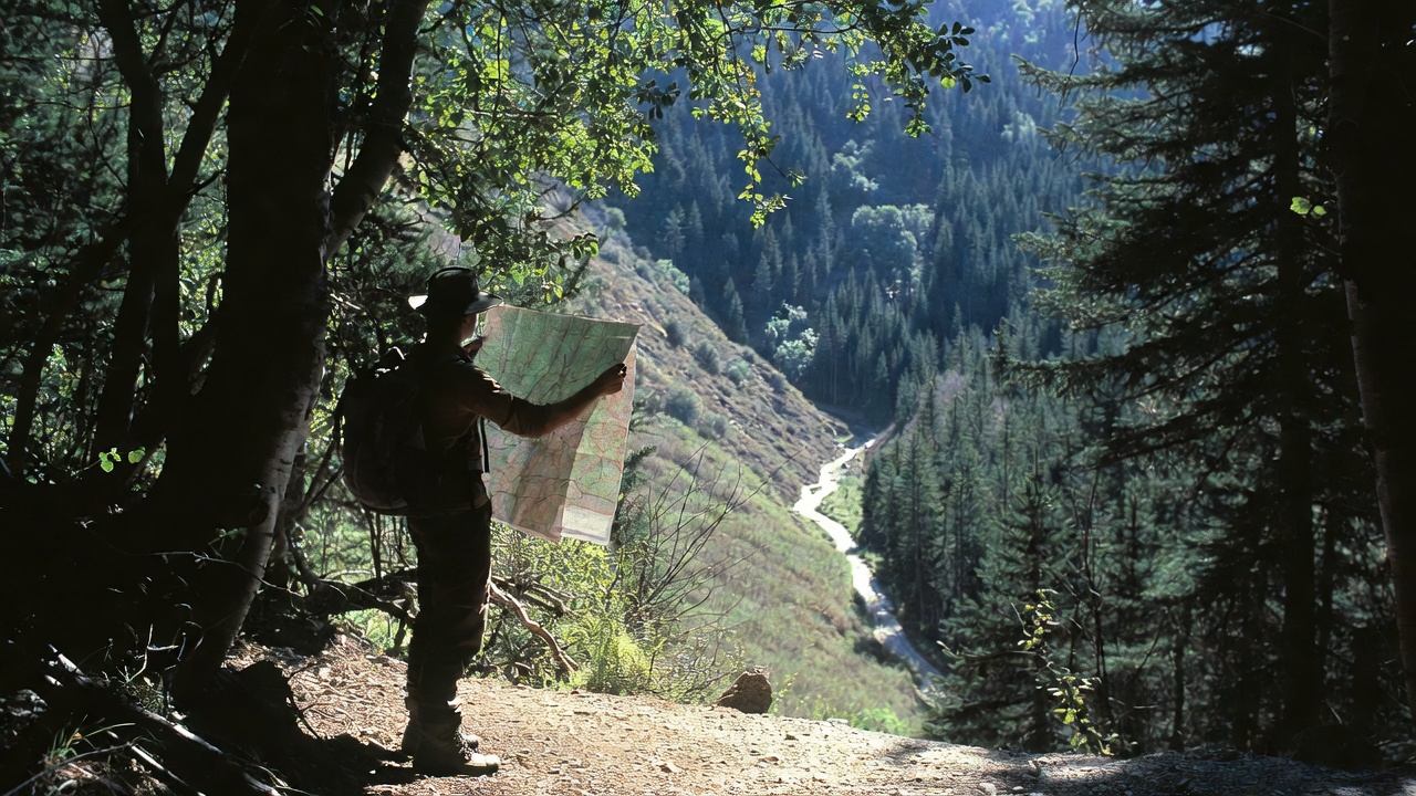 Man using topographic map on top of Valley - Popular Outdoorsman Man using topographic map on top of Valley